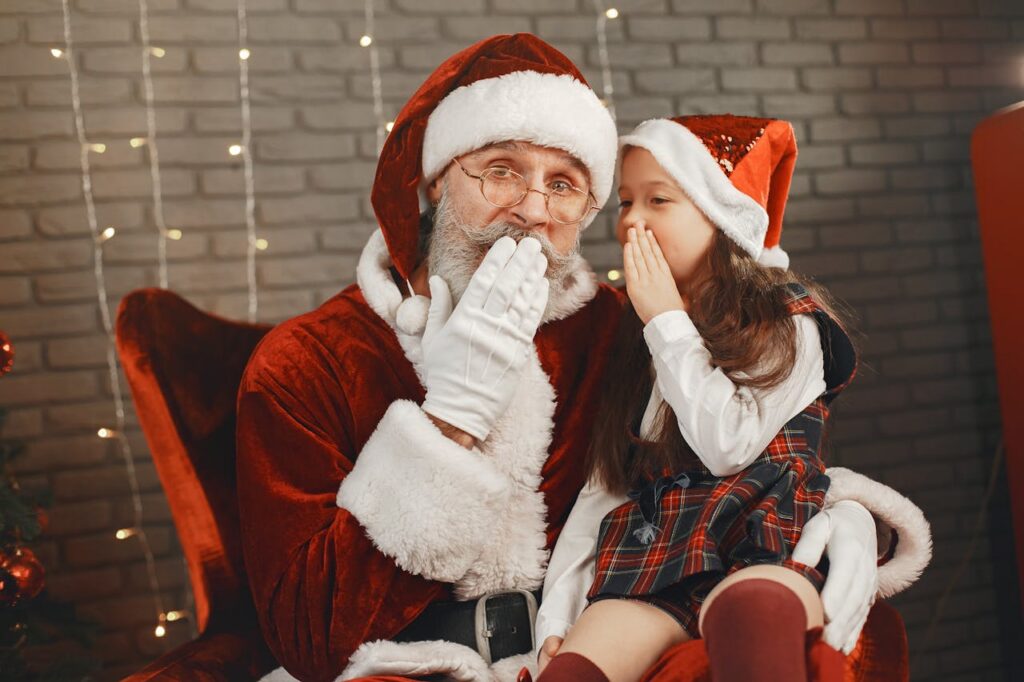pexels photo 6050485 Santa Claus and a young girl share a secret, spreading Christmas joy indoors.