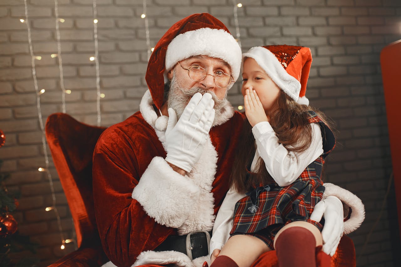 Christmas Gifts for Men in 2025 Under βΉ1000 , βΉ500 Santa Claus and a young girl share a secret, spreading Christmas joy indoors.