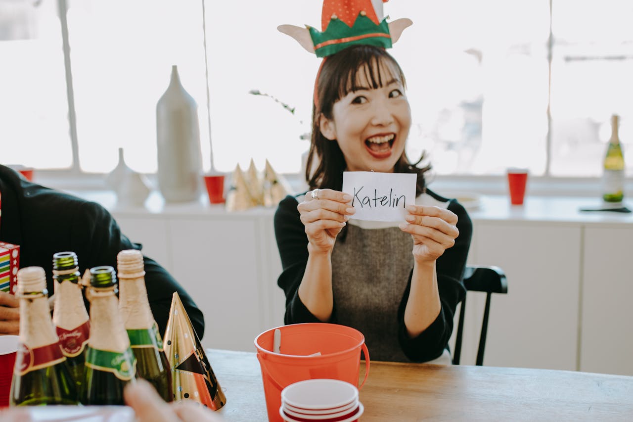 π
The Most Fun Way to Play Secret Santa Online β Try Jioplays Secret Santa Generator! Cheerful woman at a Secret Santa party holding a name card, surrounded by festive decor.